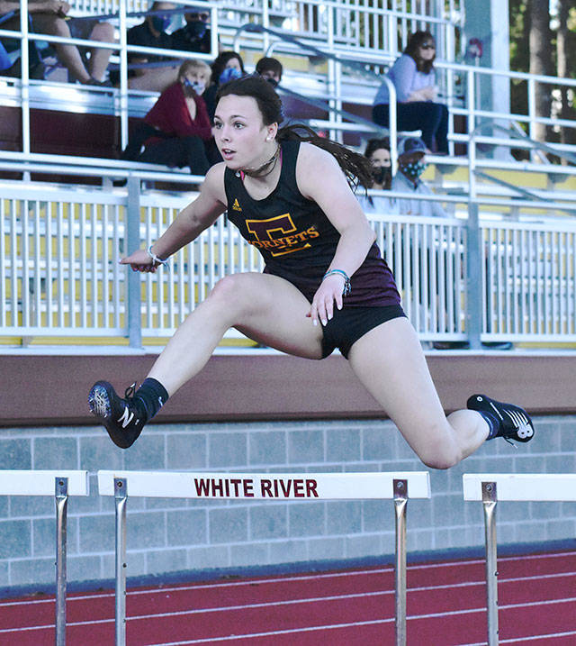 Sunny skies greet track and field athletes at Arrow Lumber Stadium Thursday afternoon. Enumclaw High made the trek across the river to take on their Buckley hosts, but headed home on the short end of the scoring. Here, Enumclaw’s Ellie DeGroot clears a hurdle on the way to victory; also, a trio of White River runners complete a first lap on the track. Photo by Kevin Hanson
