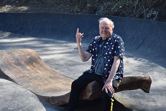 John Hillding, wearing a bacon and eggs shirt, sits atop a giant piece of concrete bacon which is part of his art installation / skatepark combination in Wilkeson. Photo by Alex Bruell