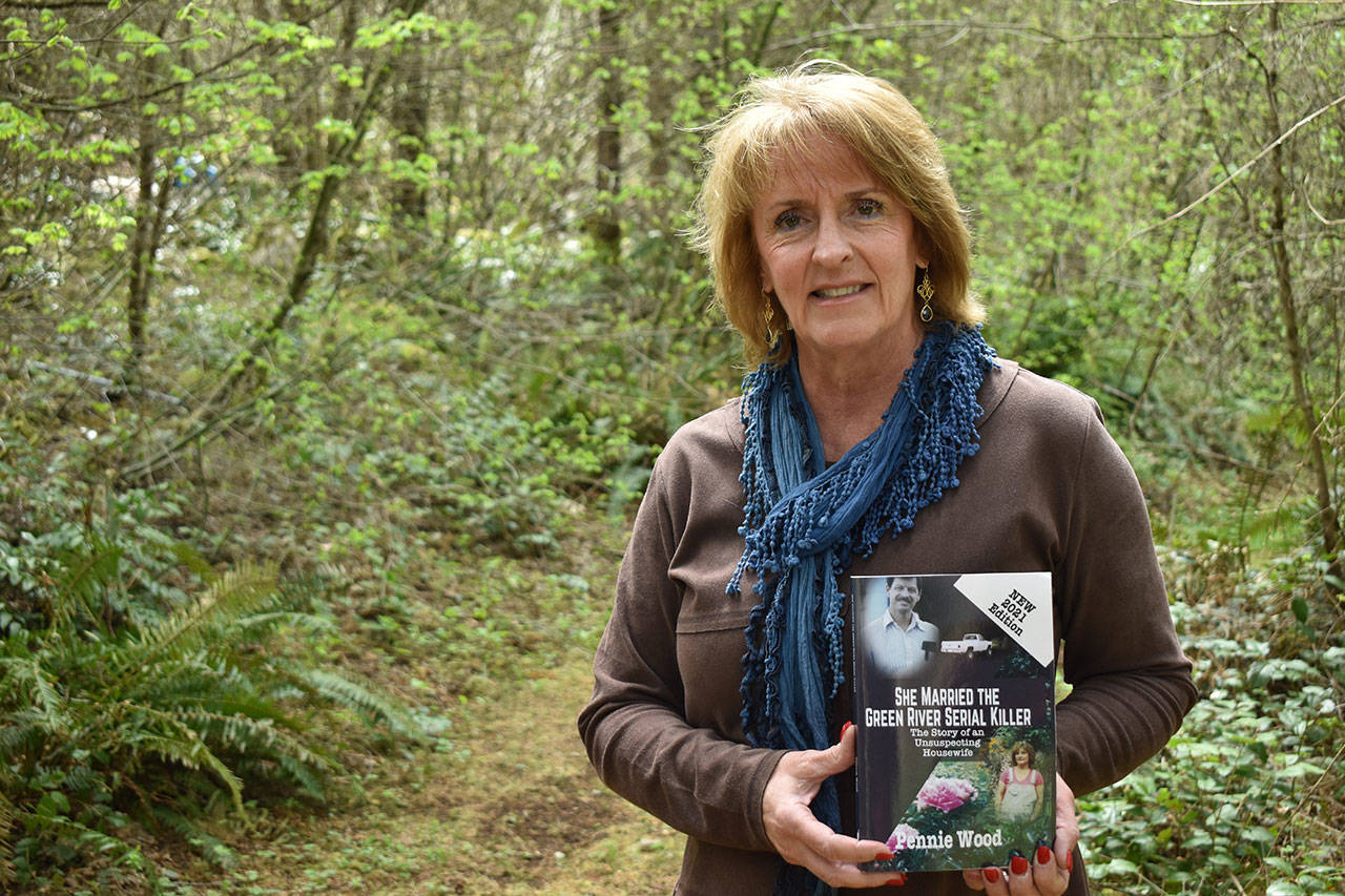 Photo by Alex Bruell
Pennie Wood holds a copy of her book “She Married The Green River Serial Killer” on a trail near her Ravensdale home April 28.