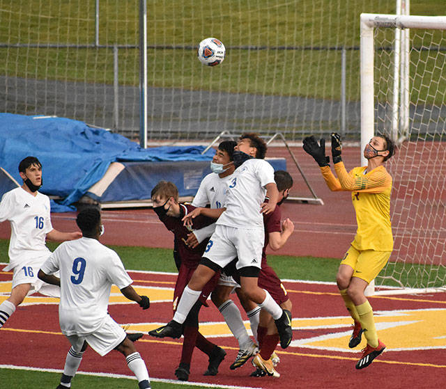 With Hornets and Trojans battling for position in front of the net, White River goalkeeper Nick Panin prepares to make a save during Thursday night’s contest on the White River High campus. In an exciting contest that went into a shootout, the visitors from Fife High escaped with a win to take the postseason title. Photo by Kevin Hanson