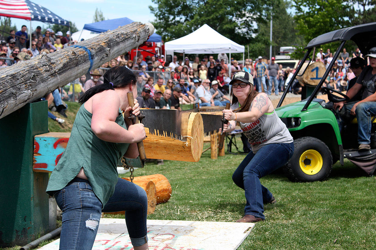 Two Buckley Log Show contestants team up to see which couple can hand-saw through a log the fastest. Photo by Ray Miller-Still