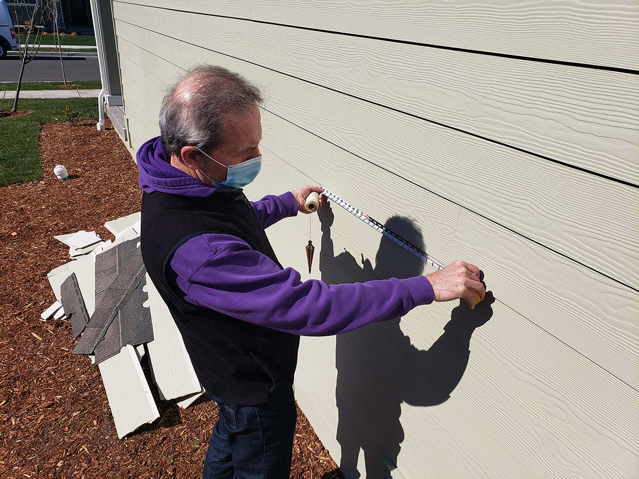 Construction expert Will Martin taking some measurement of the siding of a house in Enumclaw’s Suntop Farms. Photo by Ray Miller-Still