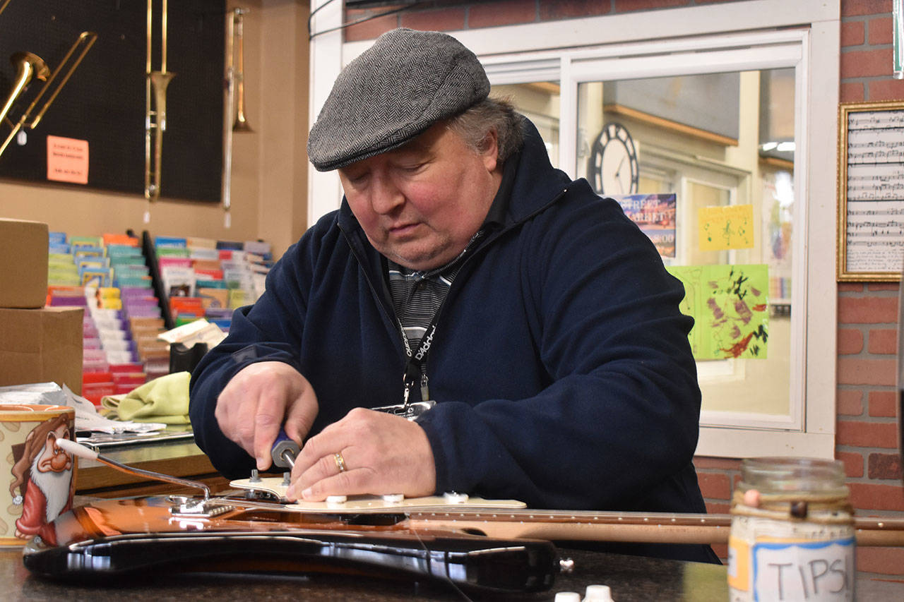 David Bozich repairs a guitar at the front desk of Enumclaw Music. Photo by Alex Bruell