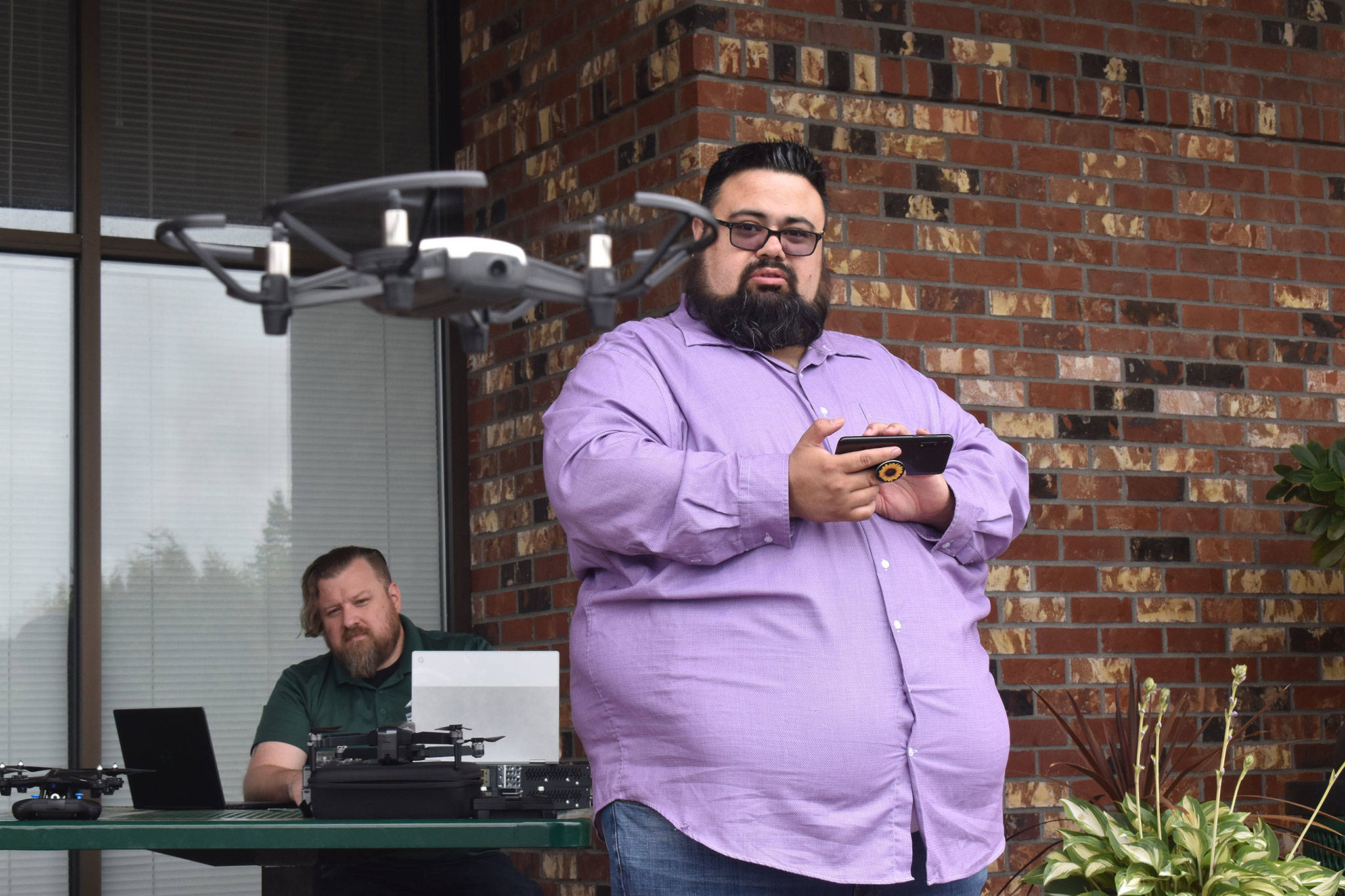 Andrew Bruce, instructor for Green River College's upcoming drone program, demonstrates the capabilities of one of his racing drones using a smartphone app outside the Enumclaw Green River campus. Photo by Alex Bruell