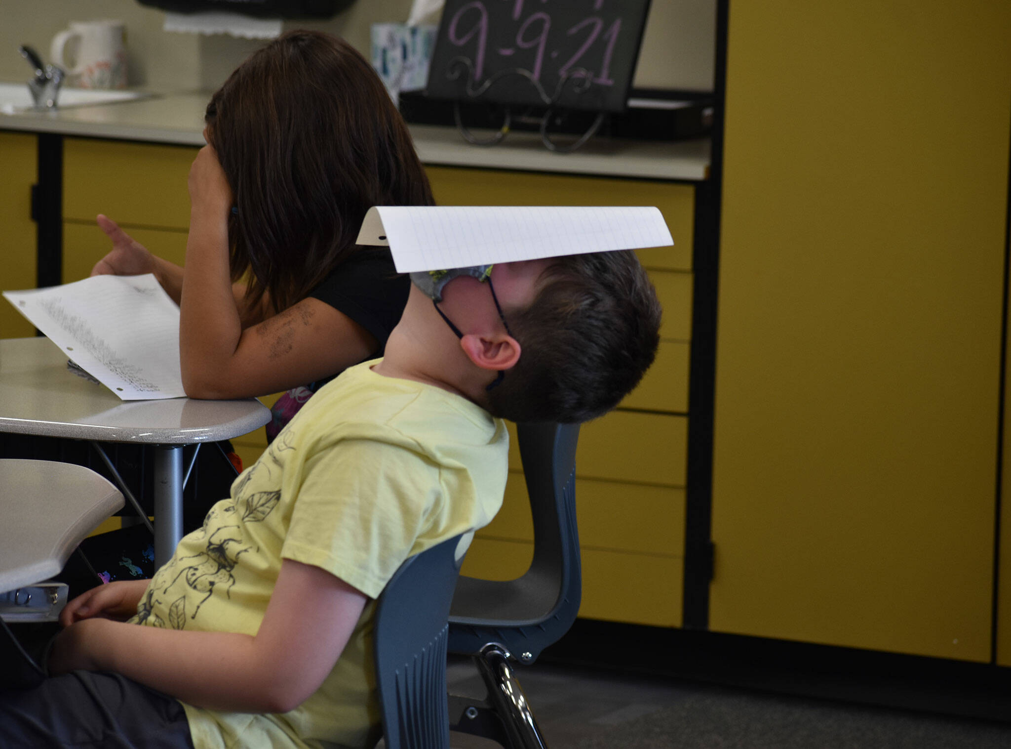 This school year and the last are different, but some things never change - like a kid’s instinct to have fun. When third grade teacher Jody Emerson asked students to place their assignments on their heads so she could collect them, one student laid back and did just so. Photo by Alex Bruell