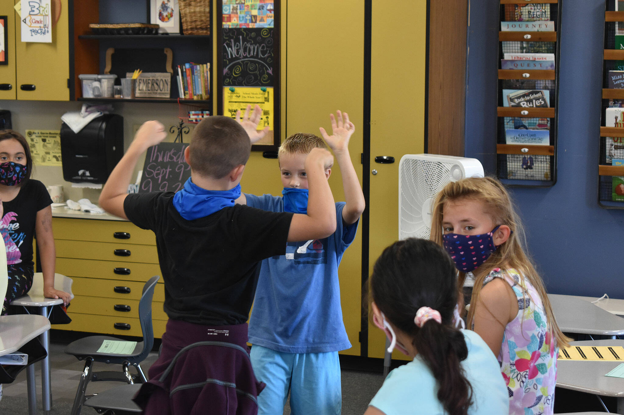 Two students greet each other in Emerson’s classroom. Photo by Alex Bruell