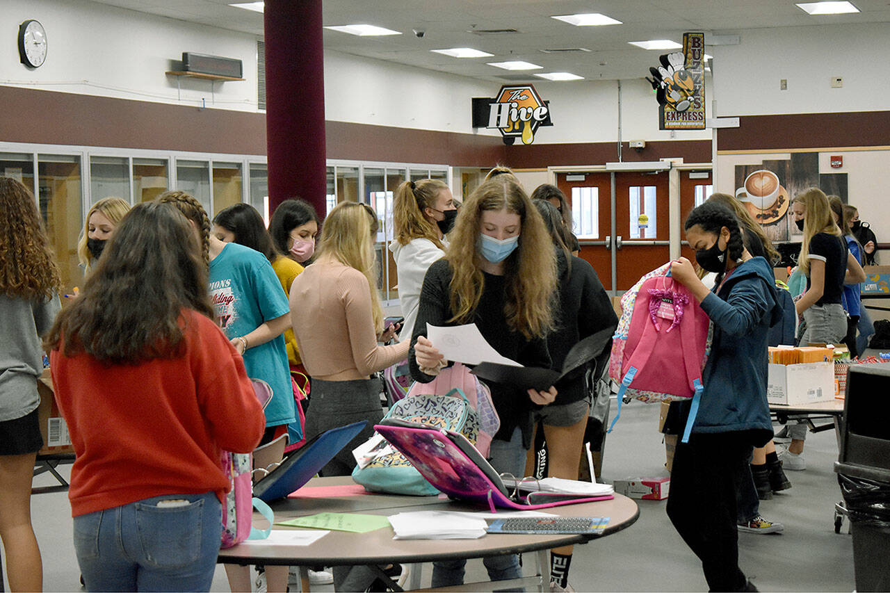 Students from Enumclaw High School and other local schools busily pack backpacks for Afghan refugees in the high school’s common area during just after the end of the school day on Sept. 20. Photo by Alex Bruell.