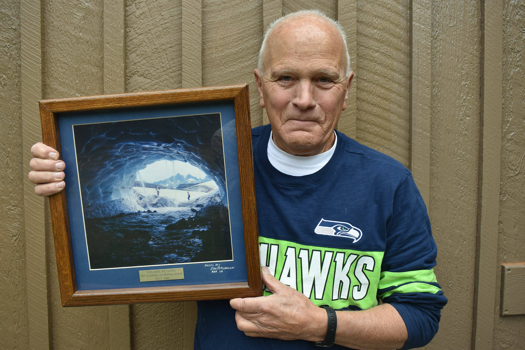 Dan Petchnick holds a framed print of his 1960 photo of the Paradise ice caves. Those ice caves are now gone due to the withering of the Paradise glacier.