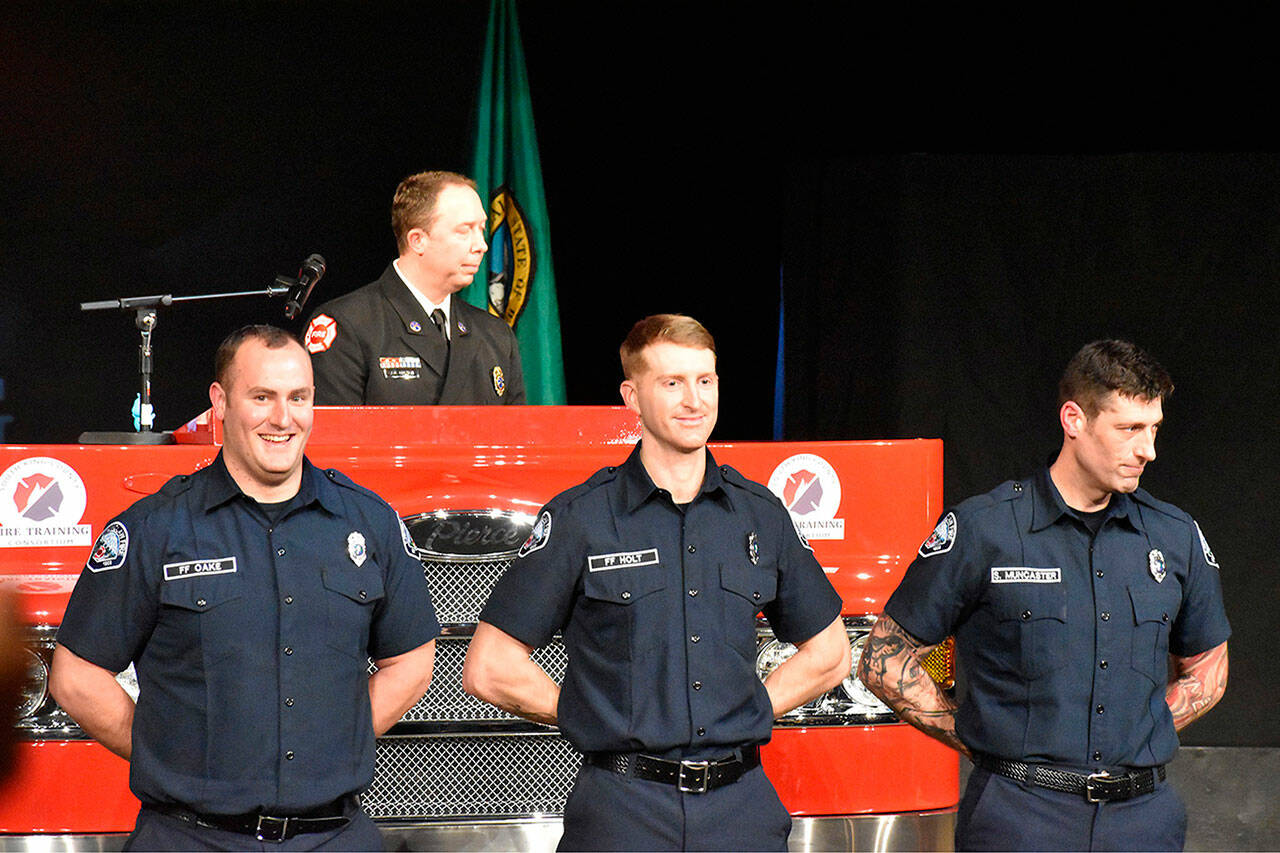 From left to right: Mitchell Oake, Ira Holt and Shane Muncaster stand after officially completing their training at the South King County Fire Training Consortium. Photo by Alex Bruell