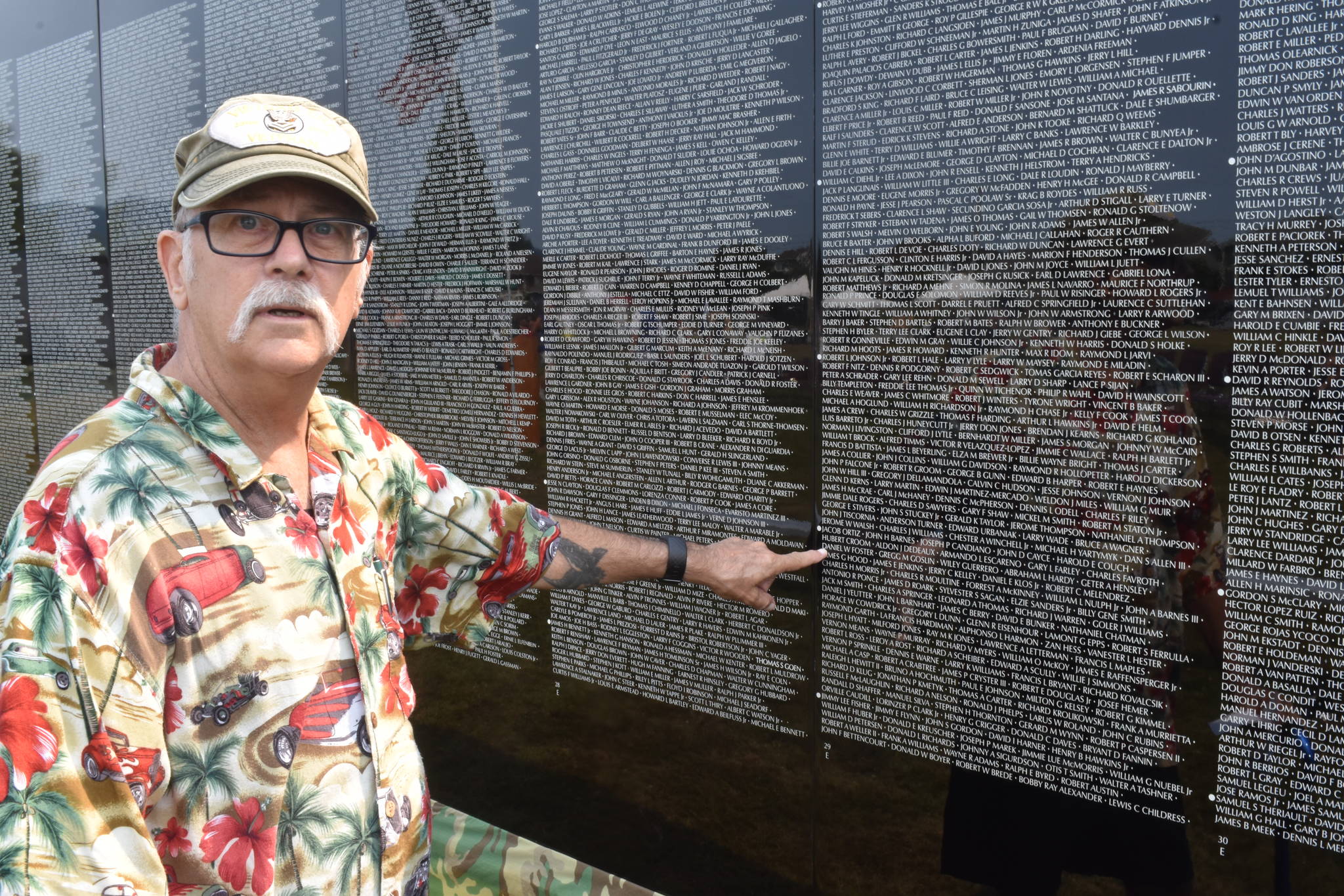 Bob Valentine points to a name on The Moving Wall in Enumclaw on Thursday.