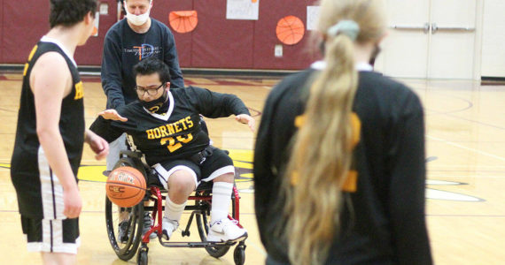 Rafael Jimenez (20) dribbles down the court with the help of local photographer Tim Dehnert. Photo by Ray Miller-Still