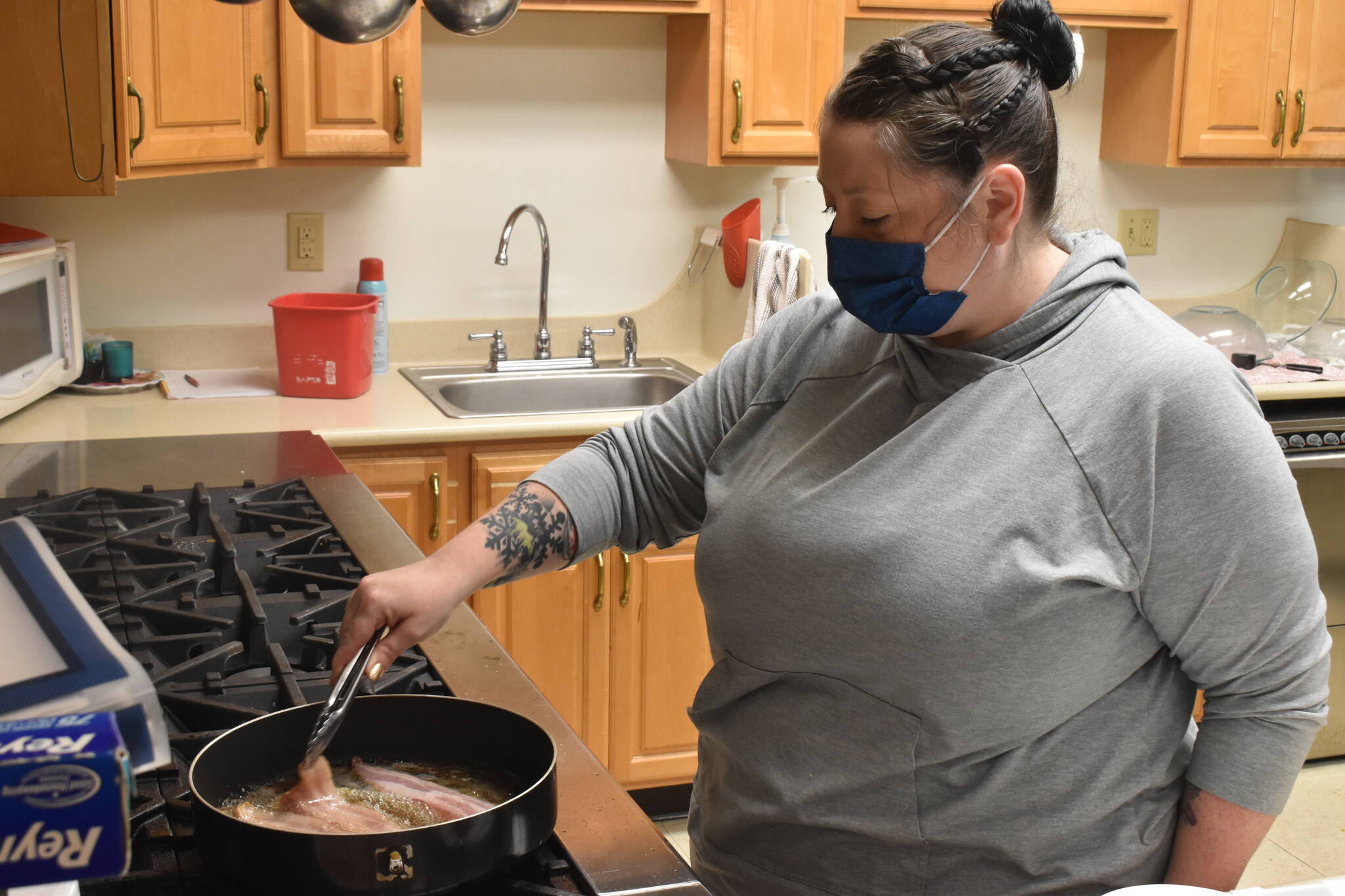 Volunteer Annie Davisson, frying bacon over the Senior Centers kitchen stovetop, helps prepare the BLT sandwiches to be delivered to seniors the morning of March 3. Photo by Alex Bruell
