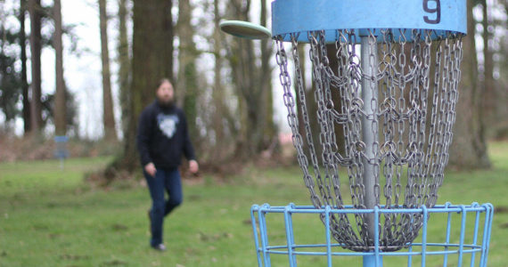 Chris Waugh makes a shot at the No. 9 hole at the Farmer's Park disc golf course in Enumclaw. Photo by Ray Miller-Still