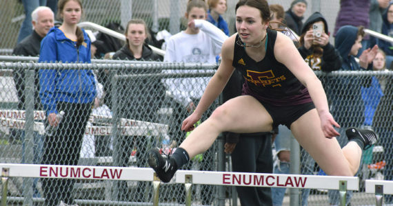 Enumclaw kicked off its Track and Field season in a drizzly afternoon bout with Fife on March 17. Ellie DeGroot, pictured here, clears a hurdle early on in the meet. Photo by Alex Bruell