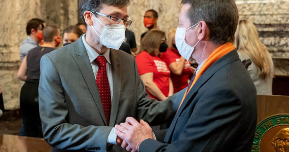 Washington Attorney General Bob Ferguson (left) speaks with Paul Kramer at the signing of bills aimed at reducing gun violence Wednesday in Olympia. Kramer’s son Will was injured in a 2016 mass shooting in Mukilteo that left three people dead. (Washington State Attorney General)