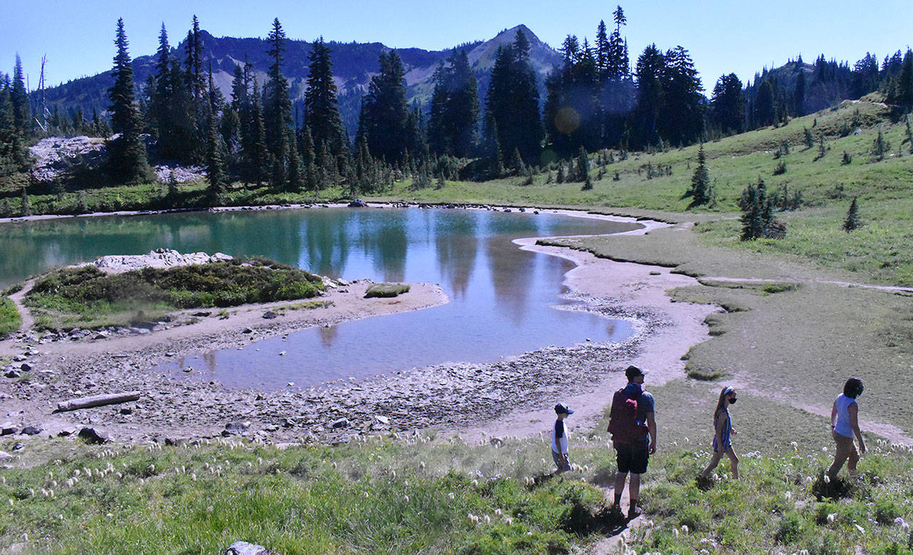 Hiking the Naches Peak Loop Trail begins and ends with the iconic view of Tipsoo Lake with Mount Rainier in the background. This photo shows a family enjoying a stop at a small alpine pond. Photo by Kevin Hanson