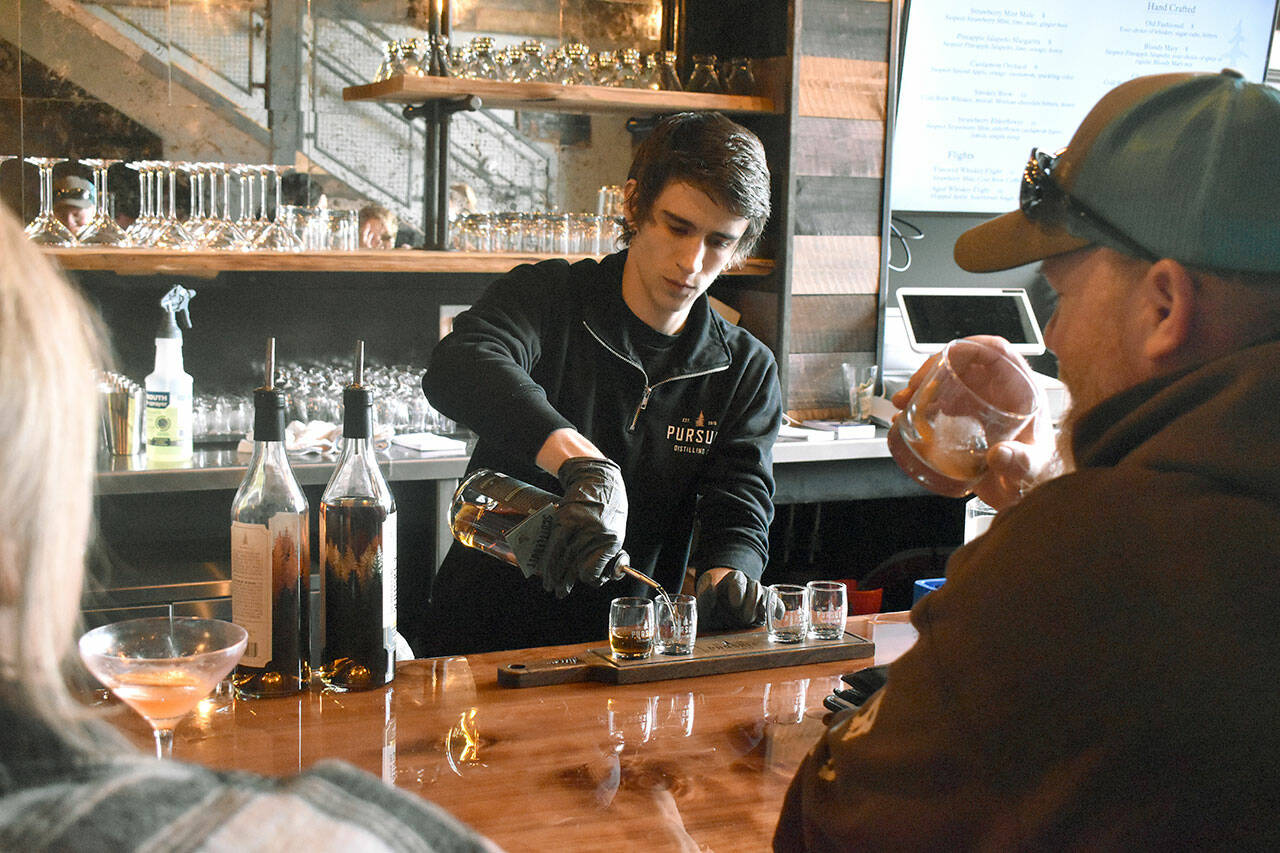 Tyler, a bartender at Pursuit Distilling's new Railroad Ave. location, pours a flight of drinks for patrons at the bar on a busy Friday night. Photo by Alex Bruell