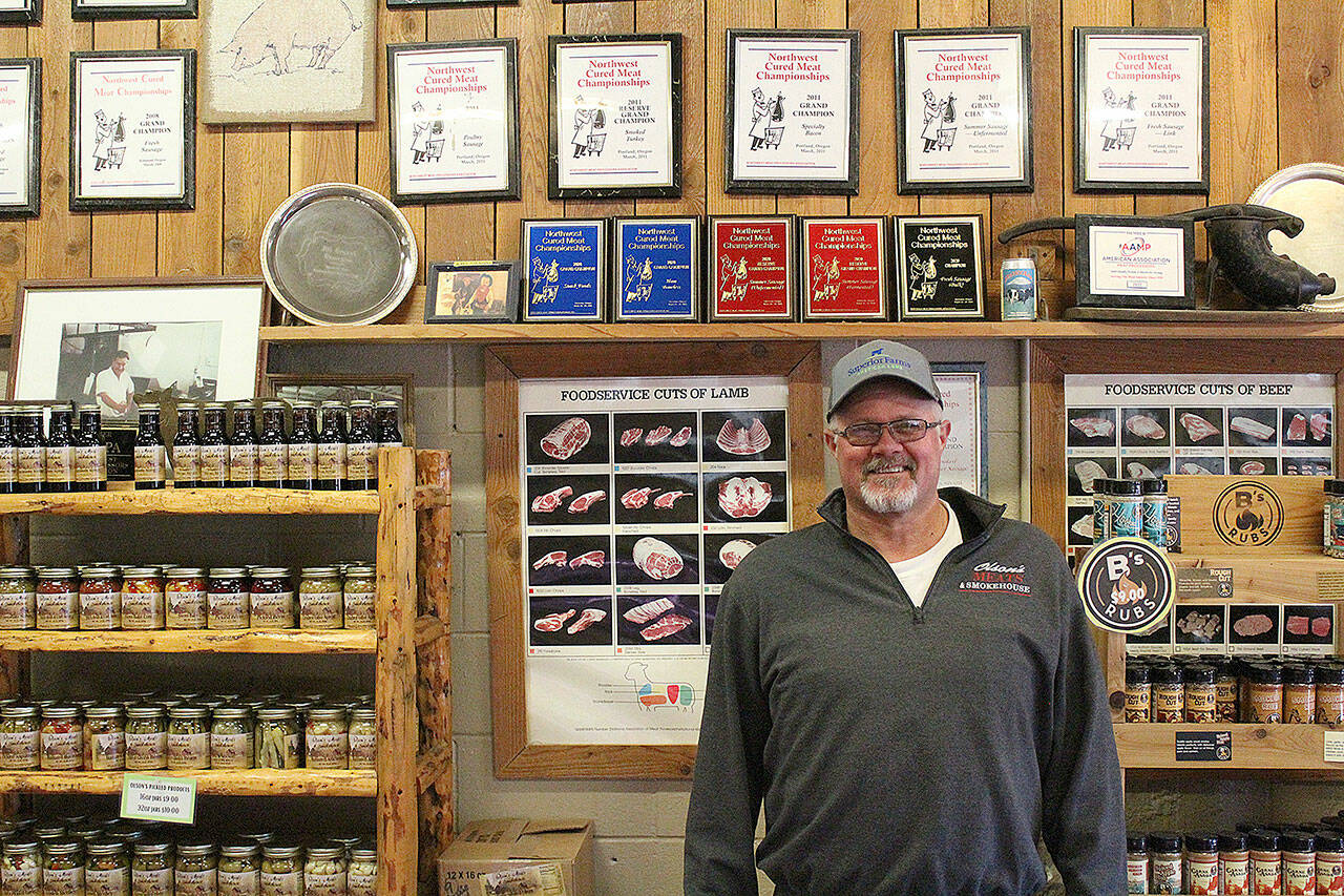 Adam Olson standing in front of Olson’s Meats numerous Northwest Meat Processors Association championship awards. Adam sausages also earned the grand champion title in the national American Cured Meats Championships in 2011. Photo by Ray Miller-Still