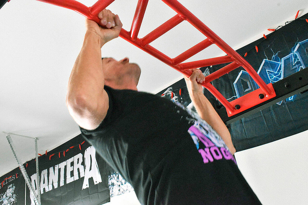 Butch Holman, running through his routine to prepare for The Murph challenge, does a few pullups in his at-home gym. Photo by Alex Bruell