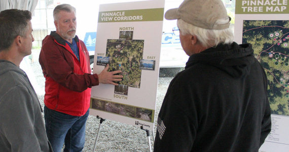 King County’s Community Partnerships and Grants Program manager Scott Thomas talks to a couple locals about the proposed tree cutting plan on Mt. Peak before the official presentation. Photo by Ray Miller-Still