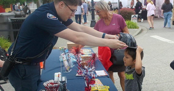 The Enumclaw Rotary's annual Street Fair was last weekend, closing down Cole Street for two days to accomodate myriad vendors, live music bands, beer gardens, bouncy toys for kids, and more. Pictured is Teo San Jose receiving some SWAG from an Enumclaw firefighter. Photos by Ray Miller-Still