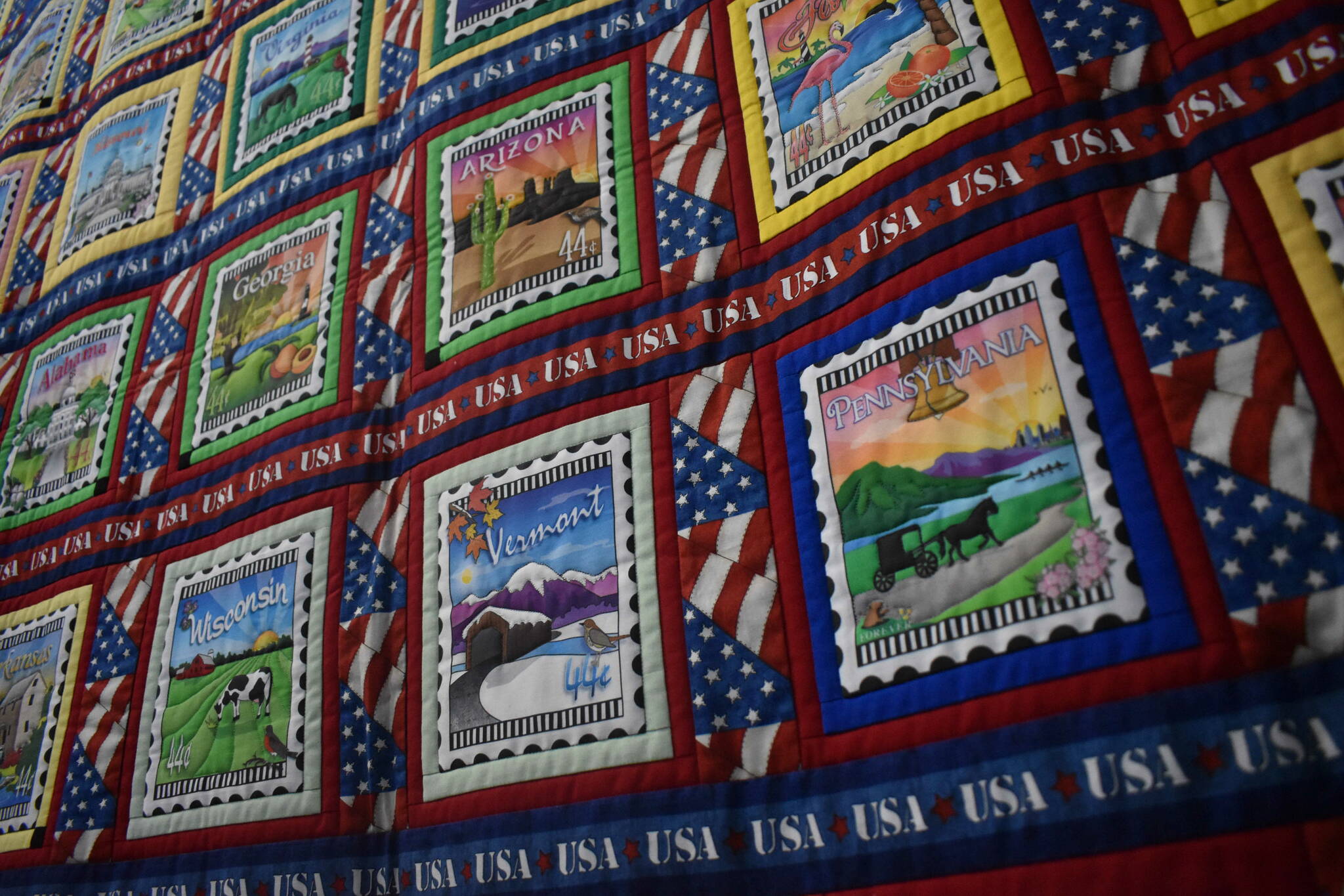 Lisa Larkin’s “A Marathoner’s Story” quilt, containing postcard designs from each of the 50 states and several other landmarks, made to commemorate her husband’s marathons in each of those locations.