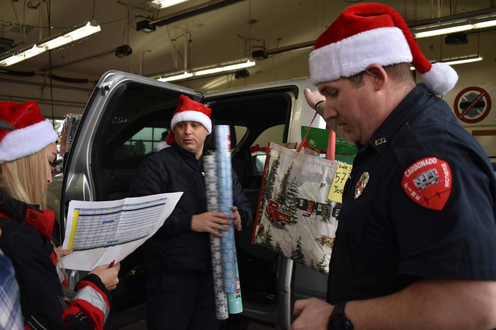 Buckley firefighters check the names on their ‘Nice’ list while loading gifts. Photo by Alex Bruell