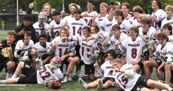 Photos by Kevin Hanson and Todd Overdorf / sonscapeimages.com/home
The Enumclaw High lacrosse team celebrates with a mid-field photo, moments after capturing the 1A/2A state championship. The Hornets took the title with a convincing victory over Orting at the Starfire complex in Tukwila. Pictured here, taken during Saturday’s contest, are McCade Walker (#16) maneuvering past an Orting defender; and Colton Paulson diving toward the goal through three Orting players.