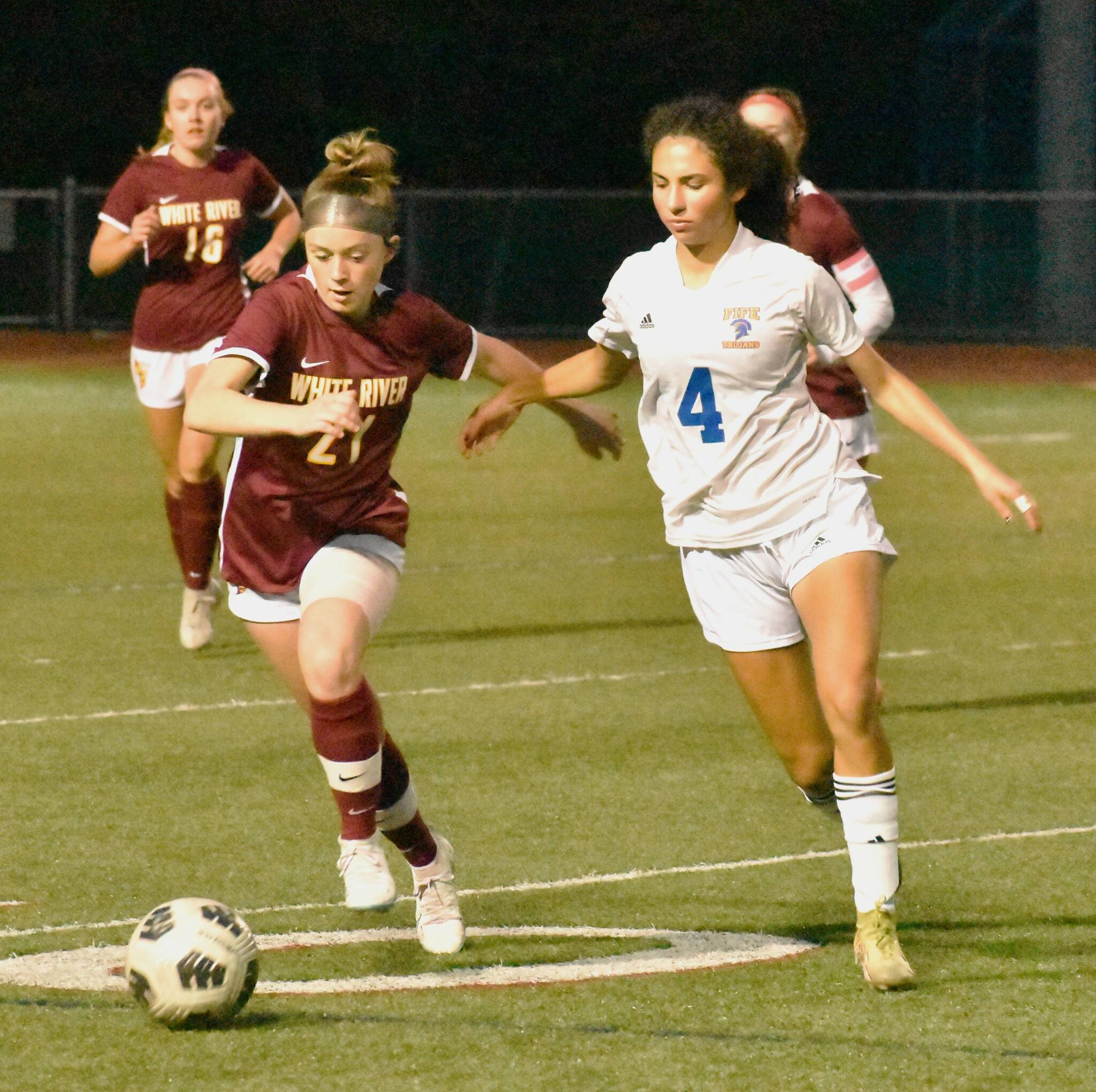 PHOTO BY KEVIN HANSON White River hosted the Fife High soccer squad on a chilly Thursday evening last week, falling 1-0 to the league-leading Trojans. In this photo, Hornet sophomore London Fuller races a Trojan for a loose ball. While White River fell to 5-3 with the loss, Fife improved to 8-0 for the season. The Trojans are the No. 1-ranked team in the state’s Class 2A ranks, according to a formula used by the Washington Interscholastic Activities Association.