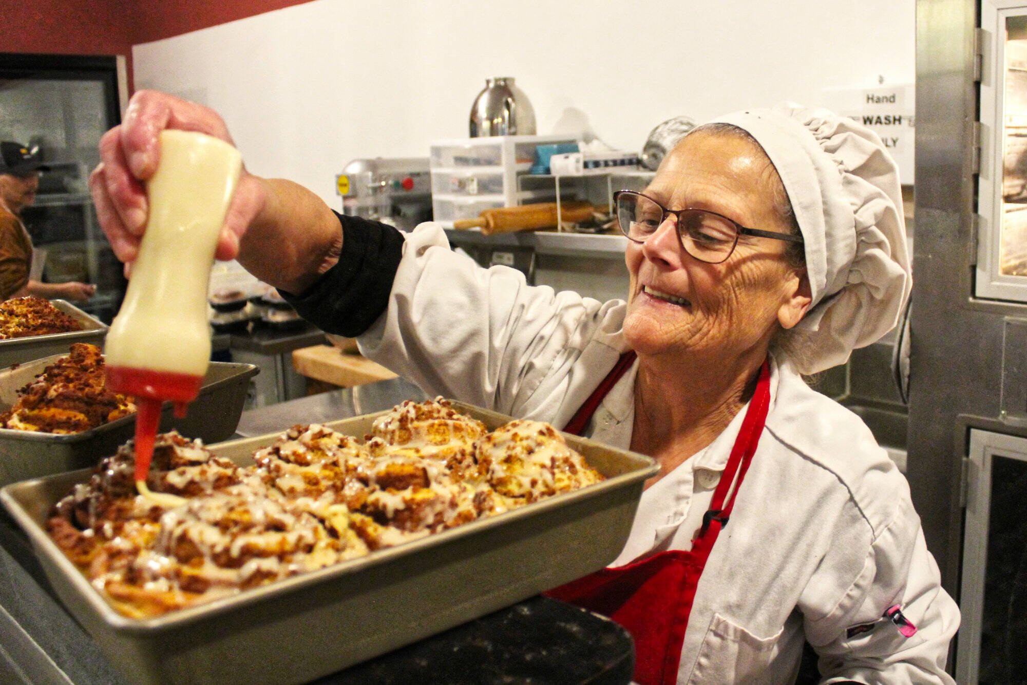 Christina King putting the drizzle on a fresh pan of banana bread cinnamon rolls at 6 a.m. Photo by Ray Miller-Still