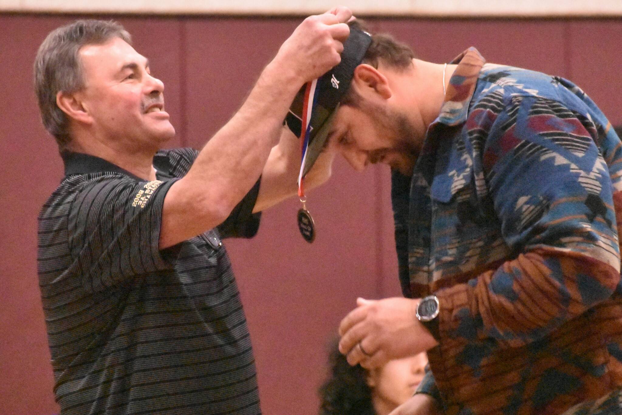 The EHS Athletic Hall of Fame welcomed three new additions the evening of January 4, all from the world of Hornet wrestling. Pictured here is Lee Reichert, who coached the 2008 state title-winning team, placing a Hall of Fame medal around the next of team member DJ Qualls. Photo by Kevin Hanson