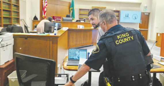 Photo by Ray Miller-Still
Andrew Baim being led out of court after opening statements concluded.