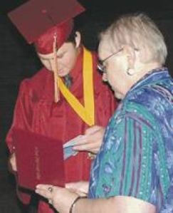 Eric Passeau reads a congratulatory card after commencement exercises Saturday while family check out his diploma.