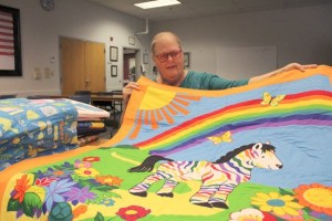 Bonnie Maiorca holds up her favorite hand-made quilt that she donated to the BLPD this month.