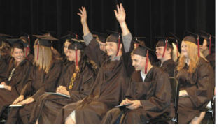 Casey Azeltine raises his hands in celebration during commencement exercises at White River High School for more than 30 Collins High graduates.
