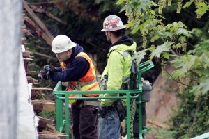 Project contractors inspect the damage to the state Route 410 overpass during the Angeline Road closure on April 28.