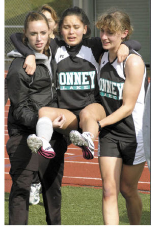 Bonney Lake girls’ track team members give a fellow teammate a helping hand after the runner developed cramps in her legs after competing in the 1