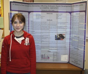 Aerin Towle stands with the summary board of her biology project. The project