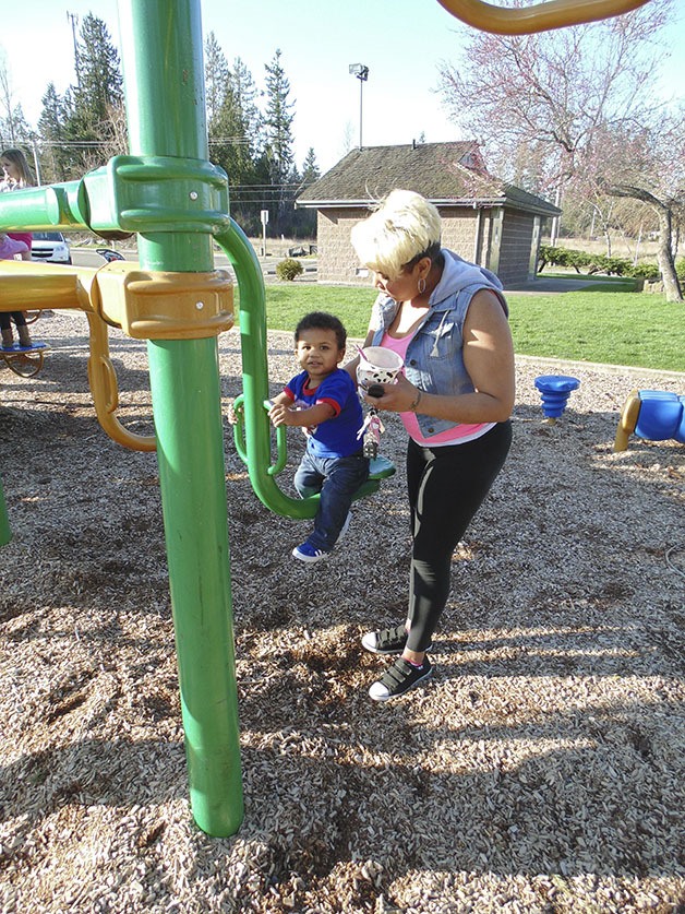 Naketa Williams (far left) and 18 month old Demari Basnight enjoy the sun while swinging at Allan Yorke Park on Wednesday