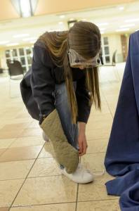 Tabitha Reynolds attempts to tie her shoe with an oven mitt to demonstrate common aftereffects of strokes.