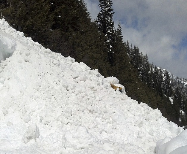 The top of the bulldozer pokes out from the snow after it was buried to the top by a natural avalanche.