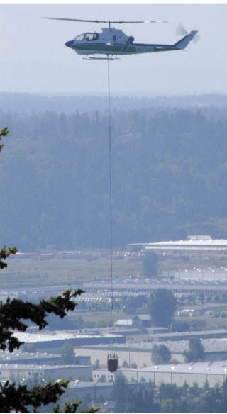 A helicopter delivers water to a July 15 brush fire on Elhi Hill along state Route 410