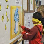 Jordan Caudillo, a first-grader at Daniel Elementary, pins the beak on Emery the Emergency Penguin. Photo by Heidi Sander.
