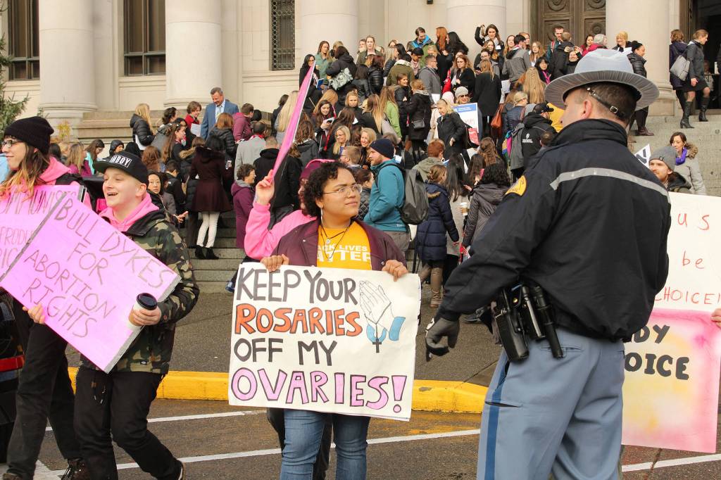 The dozen or so counter protesters on hand included Aquila Krause, shown here speaking with a Washington State Patrol officer near the Temple of Justice at the Capitol. Photo by Taylor McAvoy