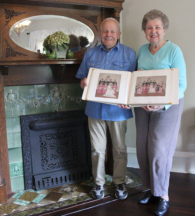 Kay (Borell) Skogan and her husband Robert holding up their original wedding album in front of the Le Sorelle Inns fireplace, suspected to be the original. Photo by Ray Miller-Still