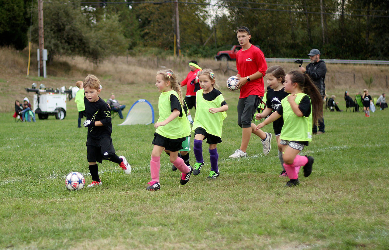 Asher Giraldo races across the Kelley Farms soccer field, followed closely by Ariana Shutly, her twin Adena, Bailey Cox, and Quinn Cunningham. Photo by Ray Miller-Still
