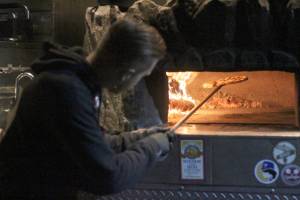 Cascadia Pizza Co. baker Stephen Hendrickson checks his pizza while waiting for business outside Headworks Brewing to pick up. Unlike many food trucks, Cascadia customers can watch everything its bakers do, since the oven is located on the outside. Photo by Ray Miller-Still