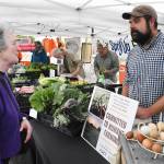 Kevin Halfrick greets a customer during last weeks debut of the Enumclaw Plateau Farmers Market. He will staff the Hell or High Water Farm tent each week. Photo by Kevin Hanson