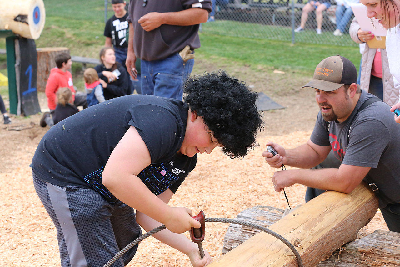 Jack Robbins finishes his try at the choke setter competition during last weekends Junior Log Show. Below, Alle Klemkow takes a moment to pose during the ax toss, and Skylar Haulet competes in the rope climb. Photos courtesy Ashley Britschgi.