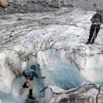 Taking a break from recording numbers, scientist Mauri Pelto balances on the walls of an ice chute to take footage of a water current on Columbia Glacier. (Zachariah Bryan / The Herald)